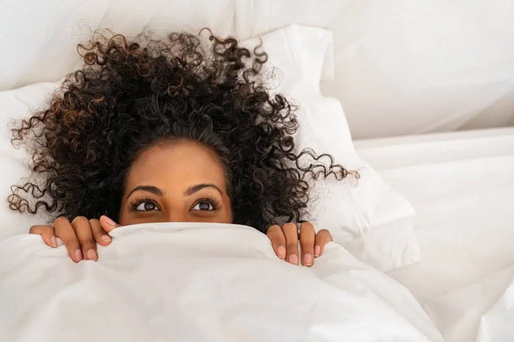 Une femme qui se cache derrière une couette