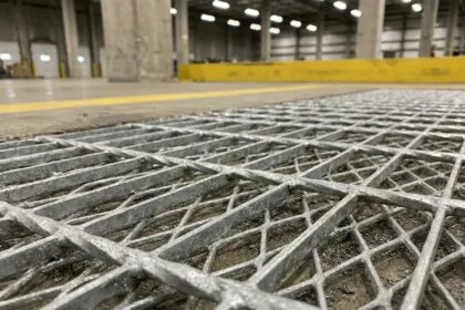 Détail de caillebotis métallique galvanisé à chaud sur sol industriel, structure maillée en acier avec revêtement zinc visible