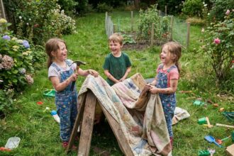 Trois enfants rient en construisant un fort dans le jardin