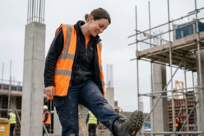 Femme ouvrière du bâtiment portant des chaussures de sécurité adaptées à la morphologie féminine sur un chantier en construction