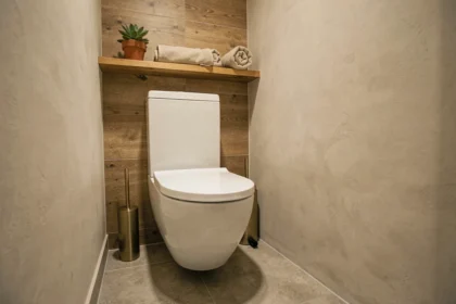 Toilette suspendu blanc sur mur en carrelage imitation bois dans une petite salle de bain chaleureuse et minimaliste