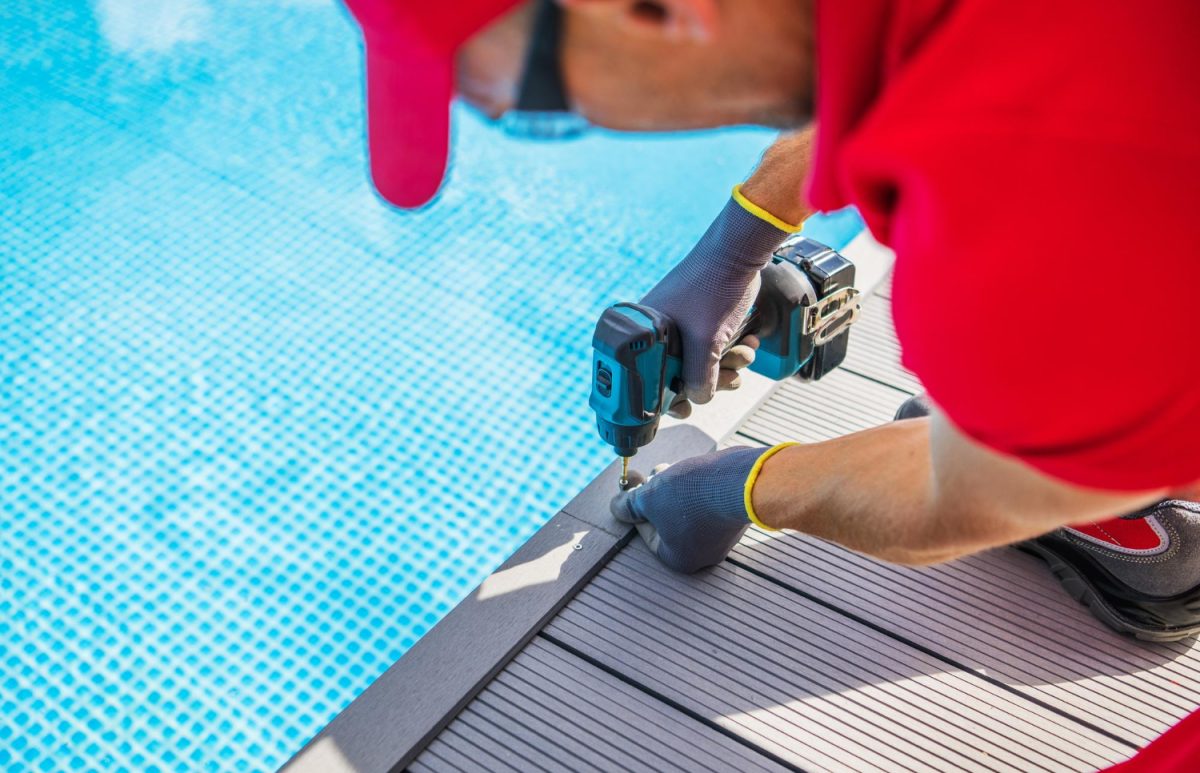Un professionnel rénove les contours d'une piscine dans un jardin privatif